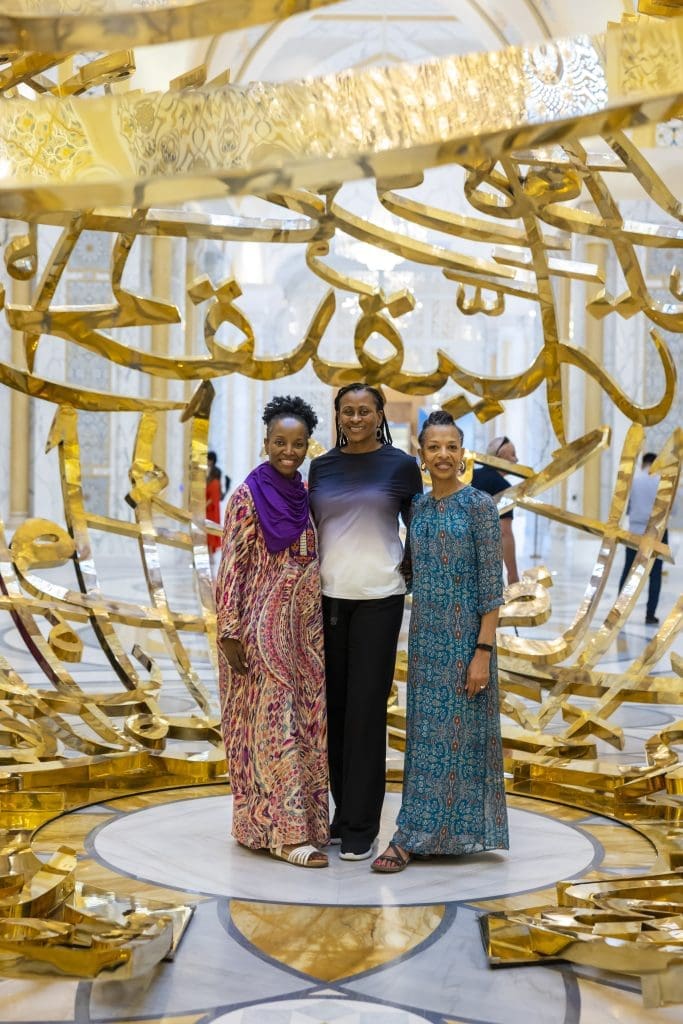 Black women in Dubai standing in front of gold sculpture