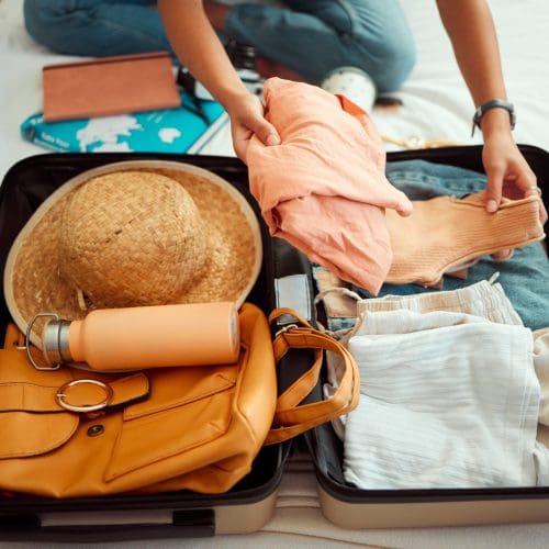 Hands, woman and suitcase on a bed for travel, adventure and summer vacation, packing and clothing. Hand, girl and luggage in a bedroom for travelling, abroad and break, relax and getaway preparation.